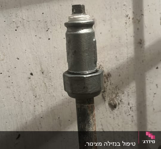 צינור מתכת עם חיבור על קיר לבן